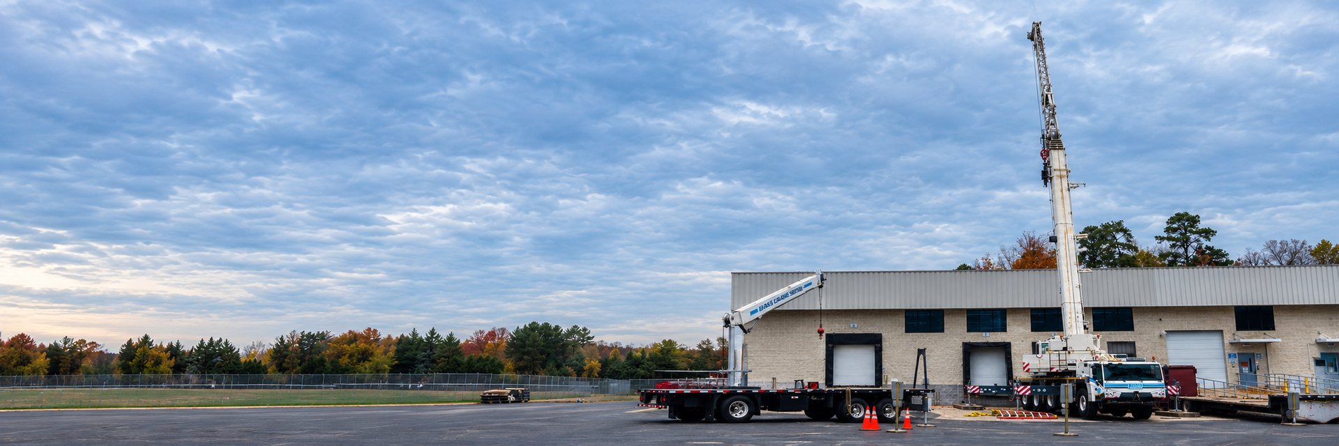 Bass Crane truck crane with boom raised at an industrial building