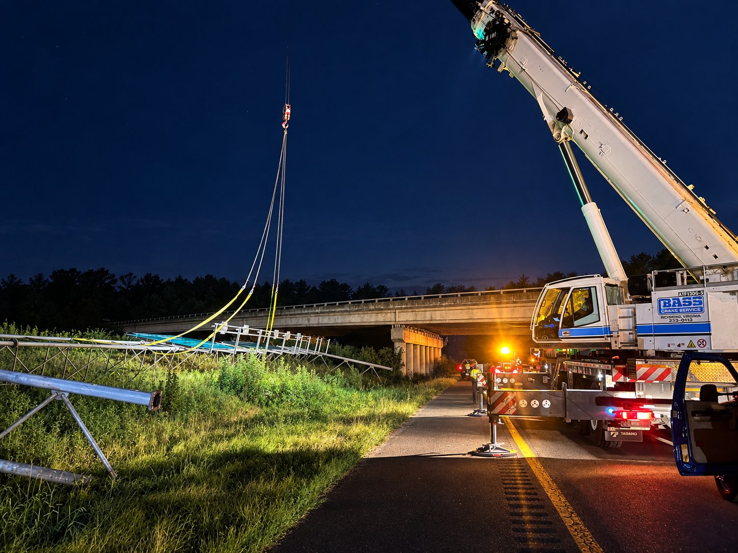 Two Bass Crane booms setting a highway sign structure at night