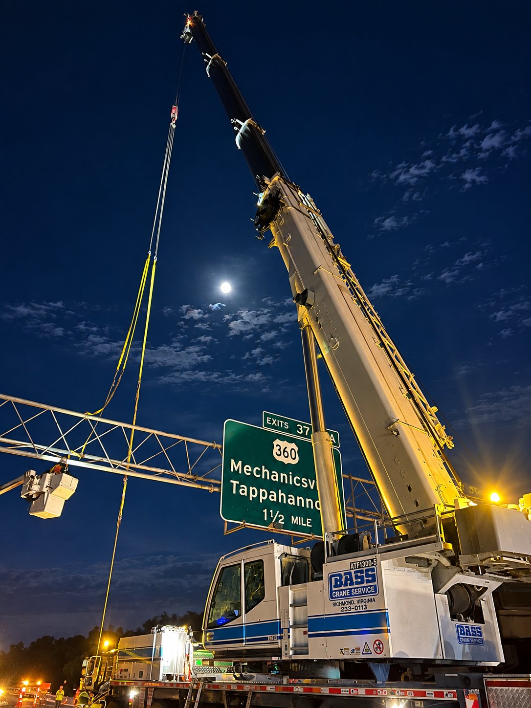 Bass Crane setting a highway sign under a full moon